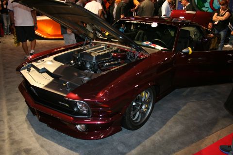 1998 Ford Crown Victoria - dark maroon custom fastback muscle car with its hood open showing the engine, low stance and large wheels at a show.