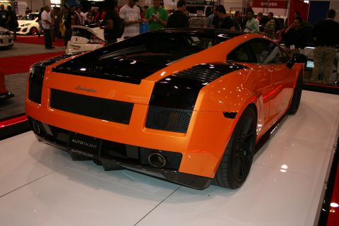 1998 Ford Crown Victoria - Rear three-quarter view of an orange and black Lamborghini Gallardo on a glossy white display platform.