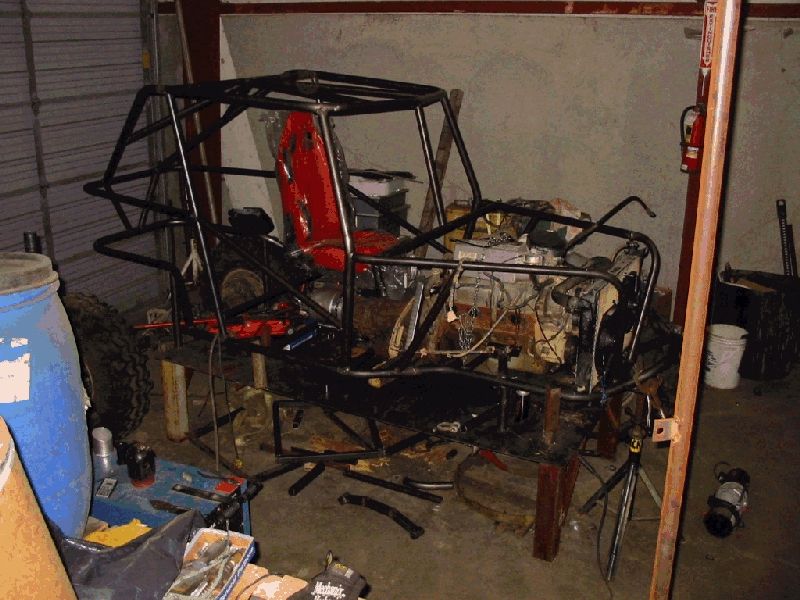 Custom buggy frame with engine and red seat, undergoing construction