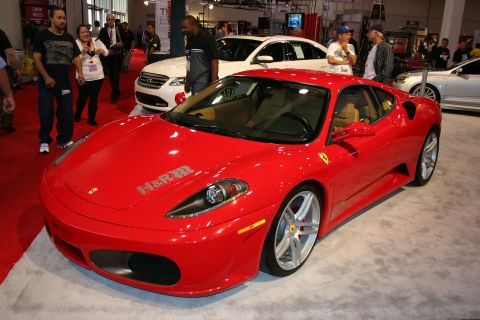 1998 Ford Crown Victoria - red Ferrari F430 coupe shown from the front three-quarter on a show floor, wearing an H&R sponsor decal.