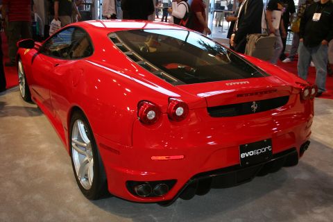 1998 Ford Crown Victoria - Rear three-quarter view of a red Ferrari F430 coupe on a show floor beside an Evosport placard.