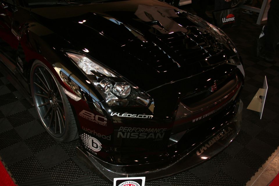 Front of black Nissan GT-R R35 with hood open and sponsor decals
