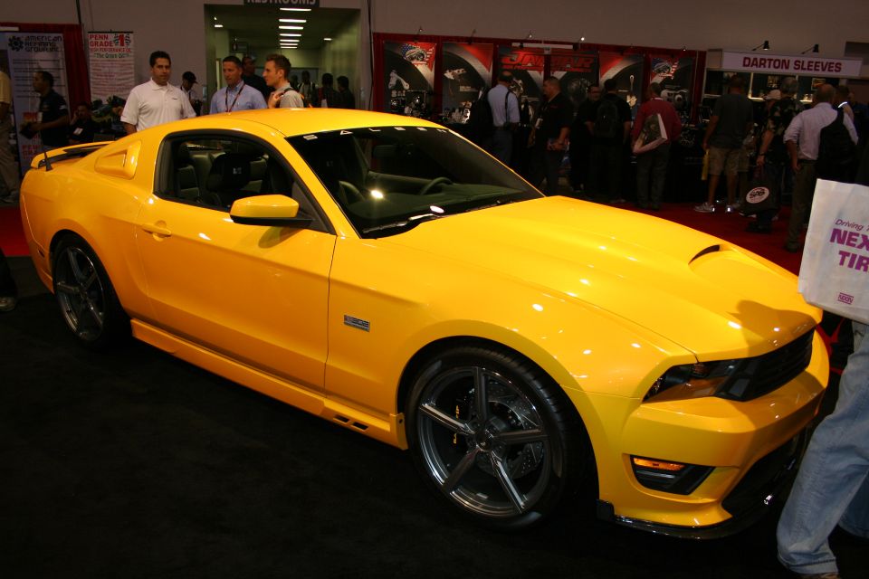 Yellow Saleen Mustang coupe on display at an indoor automotive trade show