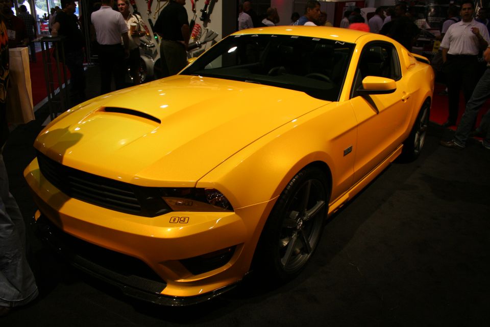 Front three-quarter view of a yellow Saleen Mustang at an indoor show