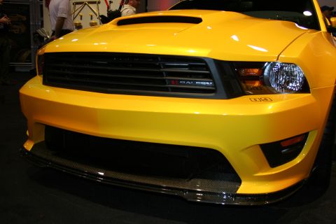 1998 Ford Crown Victoria - Close-up of a yellow Saleen Mustang front end with hood scoop, blacked-out grille and a carbon-fiber front splitter.