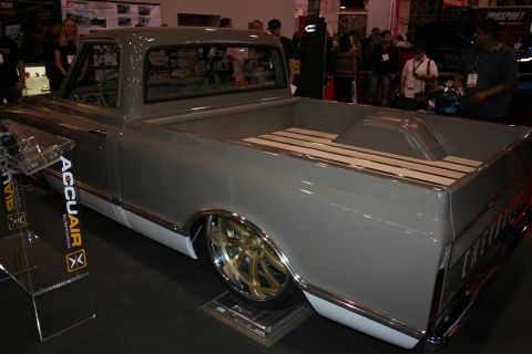 1998 Ford Crown Victoria - lowered gray custom classic pickup with a wood-slat bed floor and polished wheels on an AccuAir display stand.