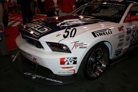 1998 Ford Crown Victoria - Front three-quarter view of a number 50 race Mustang covered in Pirelli, K&N and other sponsor decals.