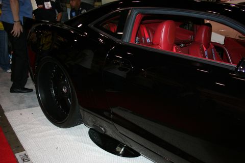 1998 Ford Crown Victoria - Side profile of a lowered black Camaro on black wheels, with a bright red interior visible through the glass.
