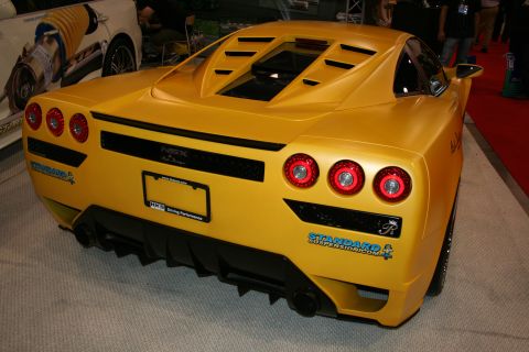 1998 Ford Crown Victoria - Rear view of a yellow custom-bodied mid-engine sports car with triple round taillights and a rear diffuser.