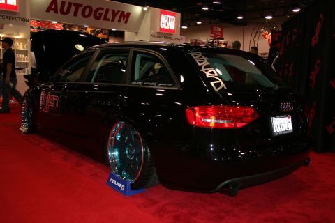 1998 Ford Crown Victoria - Rear three-quarter of a lowered black Audi wagon on custom wheels, displayed near a Falken tire stand.