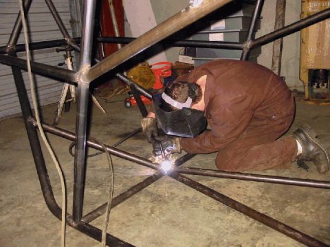 1994 Ford Bronco - A person welds a metal frame in a workshop setting.