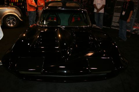 1998 Ford Crown Victoria - Front view of a glossy black custom classic Corvette Sting Ray coupe under dim show lighting.