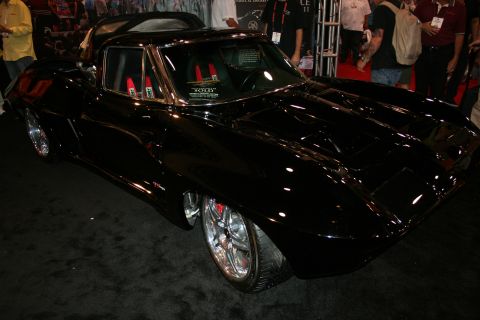 1998 Ford Crown Victoria - Front three-quarter view of a glossy black custom Corvette Sting Ray coupe on polished wheels at a show.
