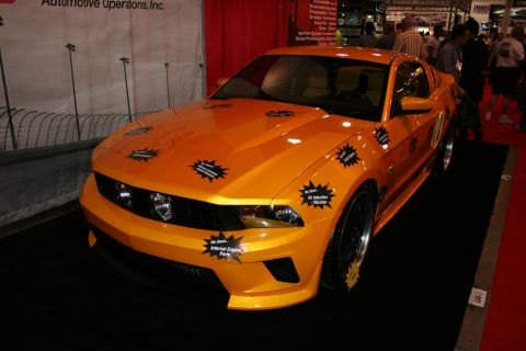 1998 Ford Crown Victoria - Front three-quarter view of an orange sports coupe with black wheels and many starburst spec stickers on its hood and fenders.
