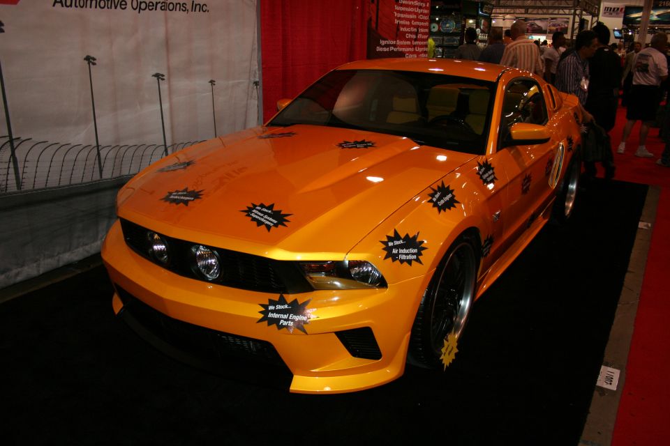 Front view of orange tuned coupe with spec stickers at indoor show
