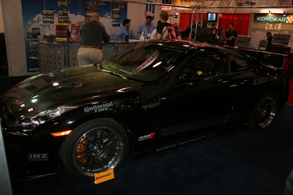 Black sports coupe with sponsor decals at indoor show booth