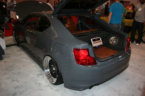 1998 Ford Crown Victoria - Rear three-quarter view of a slammed gray coupe with deep-dish wheels and an open trunk on the show floor.