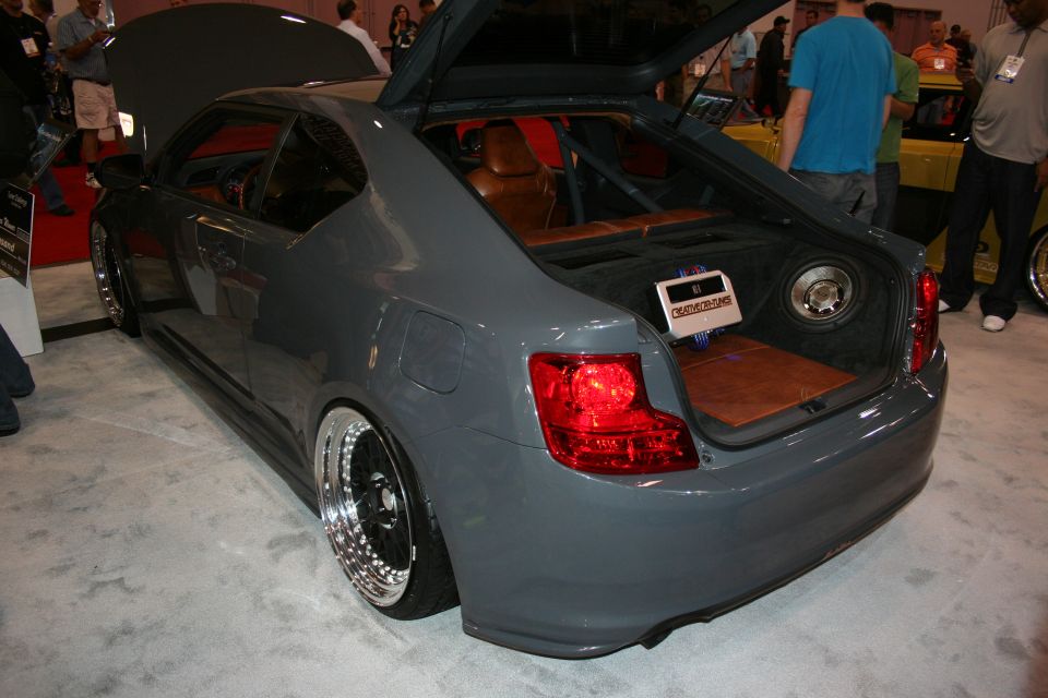 Rear view of gray slammed coupe with open trunk at show