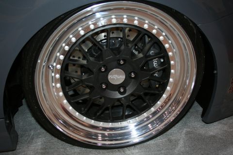 1998 Ford Crown Victoria - Close-up of a black multi-spoke alloy wheel with a polished bolted lip mounted over a brake caliper.