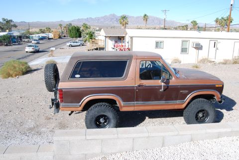 1982 Ford Bronco - This two-tone Ford Bronco is parked outdoors in a dry, desert-like environment.