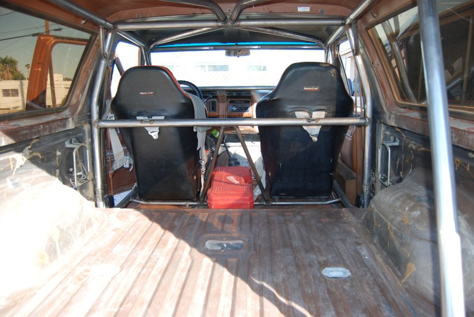 Interior view of an SUV with racing seats, roll cage, and a red toolbox