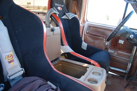 1982 Ford Bronco - The interior of a vehicle shows custom racing seats and a center console with cup holders.