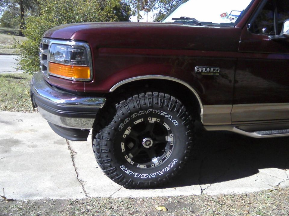 Front corner of a maroon lifted Ford Bronco with Goodyear Wrangler tire