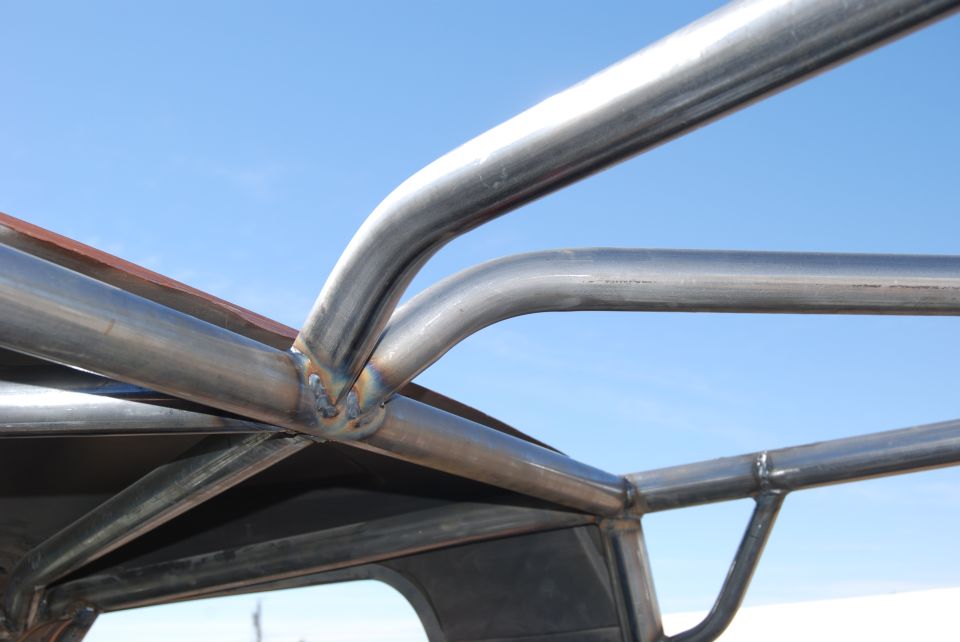 close-up of metal roll cage tubing welded together against a blue sky