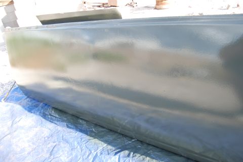 1982 Ford Bronco - A green painted panel, possibly a car door or fender, rests on a blue tarp outdoors.