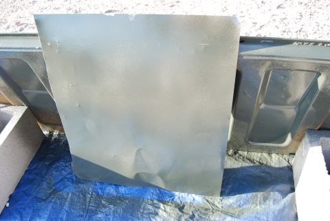 1982 Ford Bronco - Dented car door panel, painted and placed on a blue tarp for storage or work.