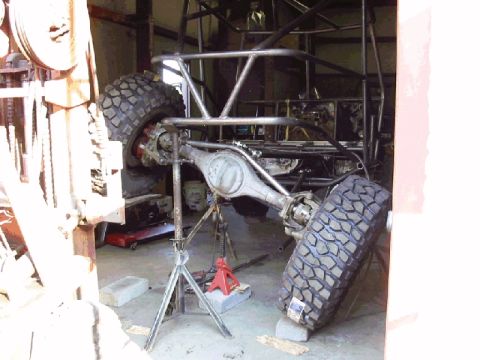 1994 Ford Bronco - The chassis of a custom off-road vehicle is shown undergoing work in a garage setting.