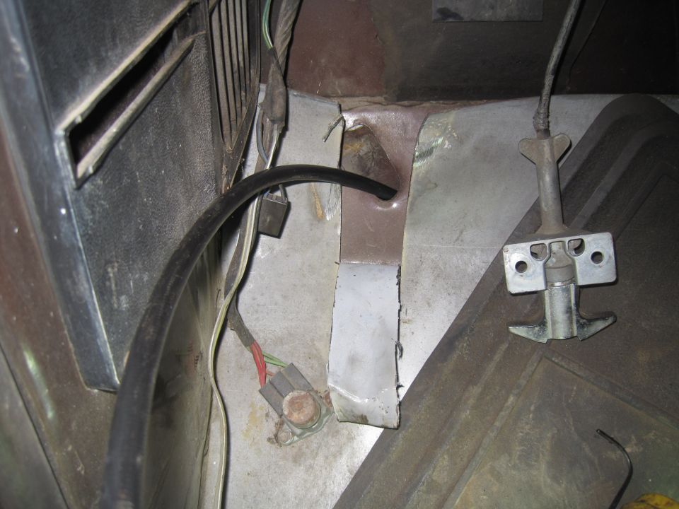 Under dash view showing wiring harness, a black hose, and a metal latch mechanism
