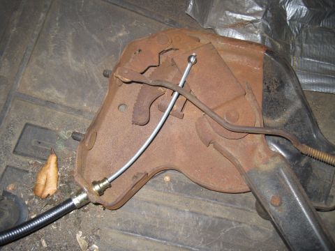 1979 Ford Bronco - Close-up of a rusty parking brake assembly with a brake cable attached.