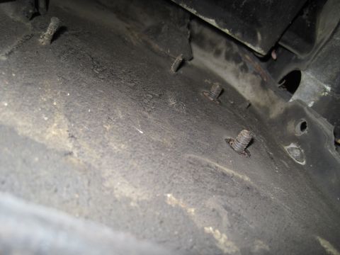 1979 Ford Bronco - Close-up view of the undercarriage of a vehicle, focusing on several bolts and the textured surface.