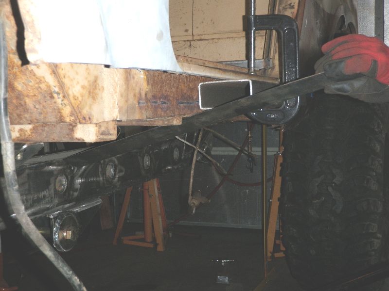 Vehicle frame with rust and new metal tubing being clamped for modification