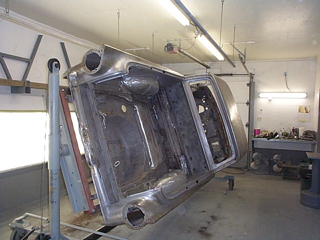 1957 Ford Ranchero body shell, bare metal, suspended on a rotisserie in a workshop