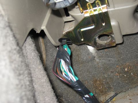 2005 Jeep Wrangler - A bundle of wires is secured with a zip tie and electrical tape beneath the dashboard, likely for a sub-woofer installation.