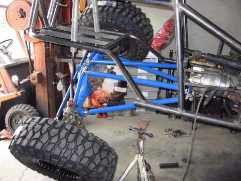 1994 Ford Bronco - Custom off-road buggy frame under construction, large tires and blue suspension parts.