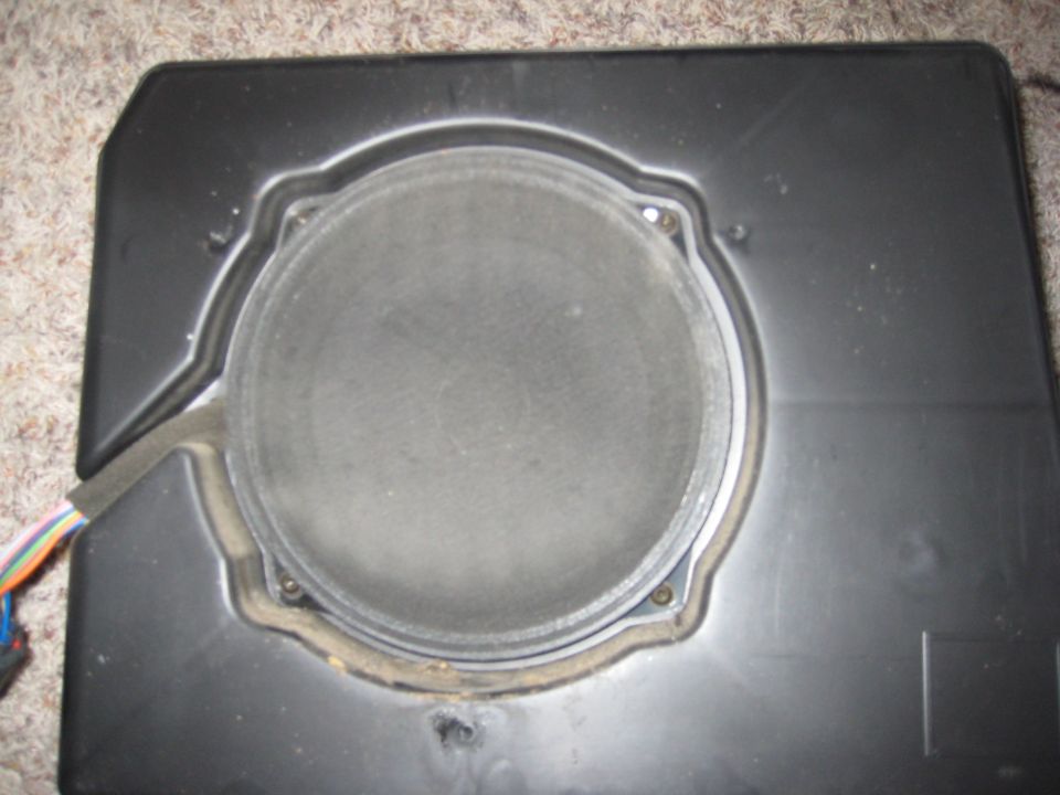 Speaker in a black plastic enclosure with wires attached. Supermotors.net logo visible