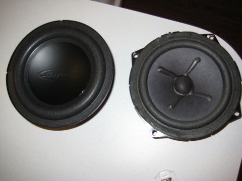 2005 Jeep Wrangler - A subwoofer with a 'Basswerk' logo and a standard car speaker are shown side-by-side on a white surface.