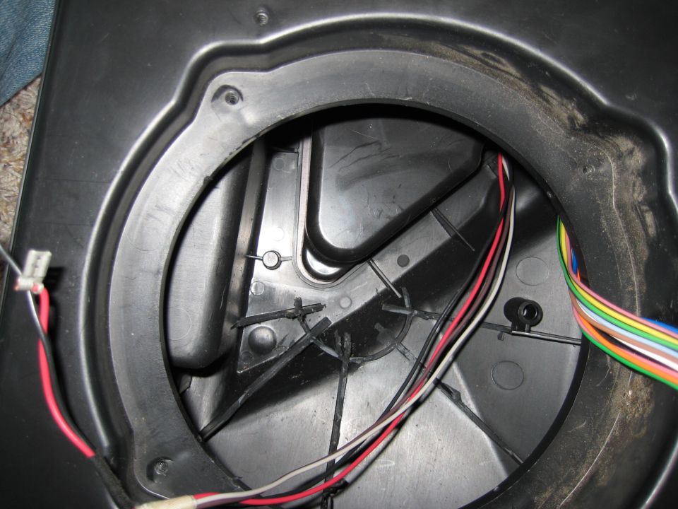 Empty round speaker mounting hole in black plastic panel with loose wiring