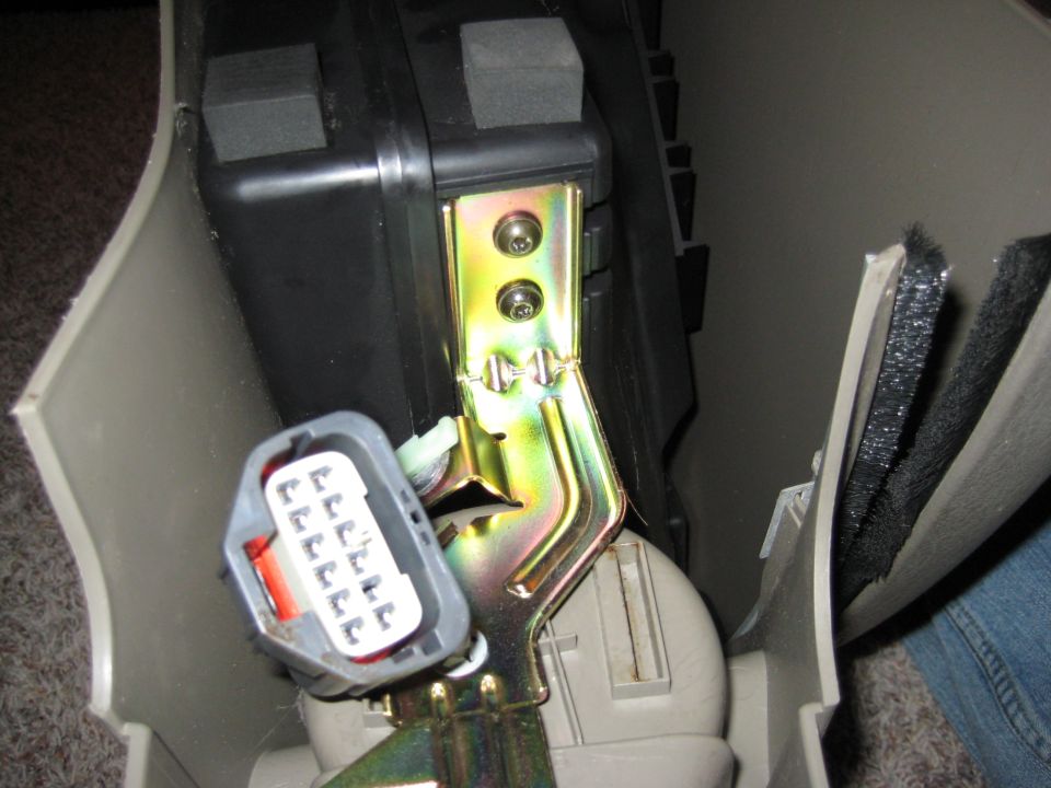 Gray electrical connector and yellow metal bracket inside a vehicle