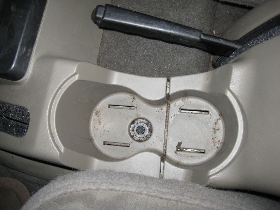 Overhead view of a dirty tan plastic dual cup holder on a vehicle center console