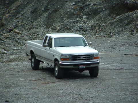 1989 Ford Bronco - This white Ford F-250 pickup truck, likely from the early to mid-1990s, is parked on a gravel surface with a rocky incline in the backgroun…