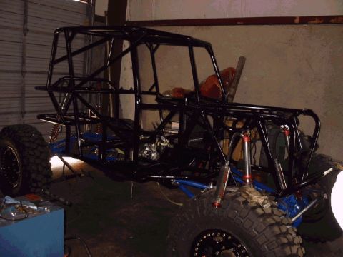 1994 Ford Bronco - The skeletal frame of a custom off-road vehicle is shown in a garage setting.