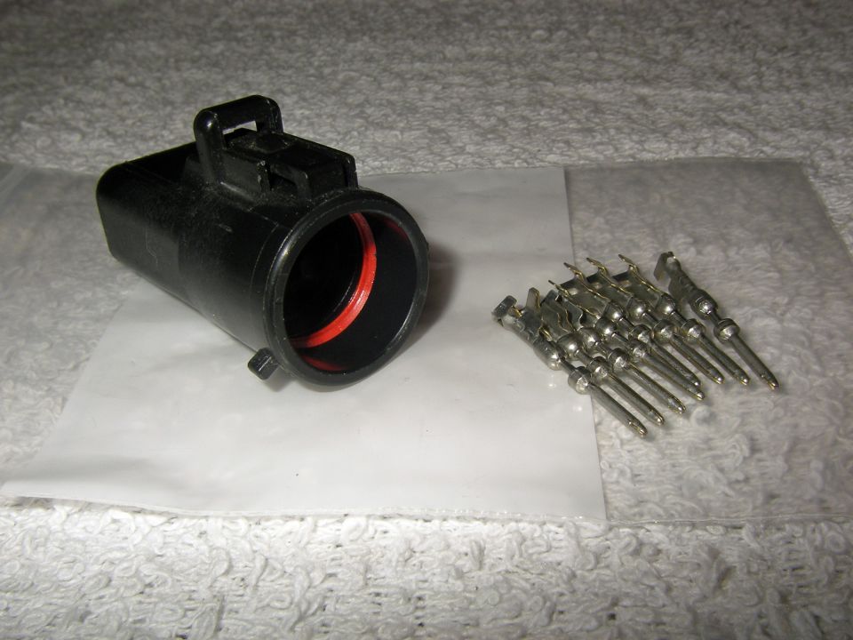 Black electrical connector housing with red seal and loose metal terminal pins