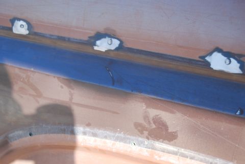 1982 Ford Bronco - A close-up view of a car's body panel undergoing repair work, with blue tape and primer visible.