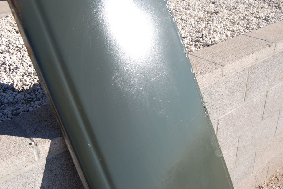 Green car door panel leaning against a block wall