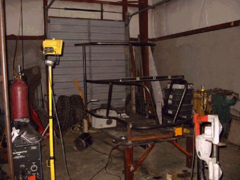 1994 Ford Bronco - A custom vehicle frame is under construction in a workshop, surrounded by tools and equipment.