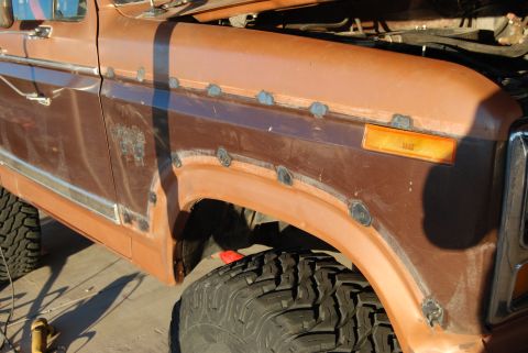 1982 Ford Bronco - This Ford truck shows signs of body repair work on the fender, with visible welds and some rust.